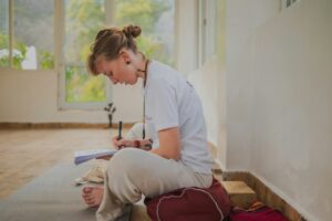 Person writing in a journal beside a cup of tea while practicing a calm daily routine at home.