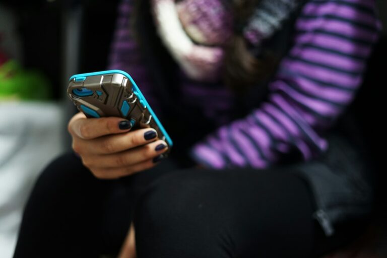 Teen and parent talk calmly at a kitchen table while a smartphone rests nearby.