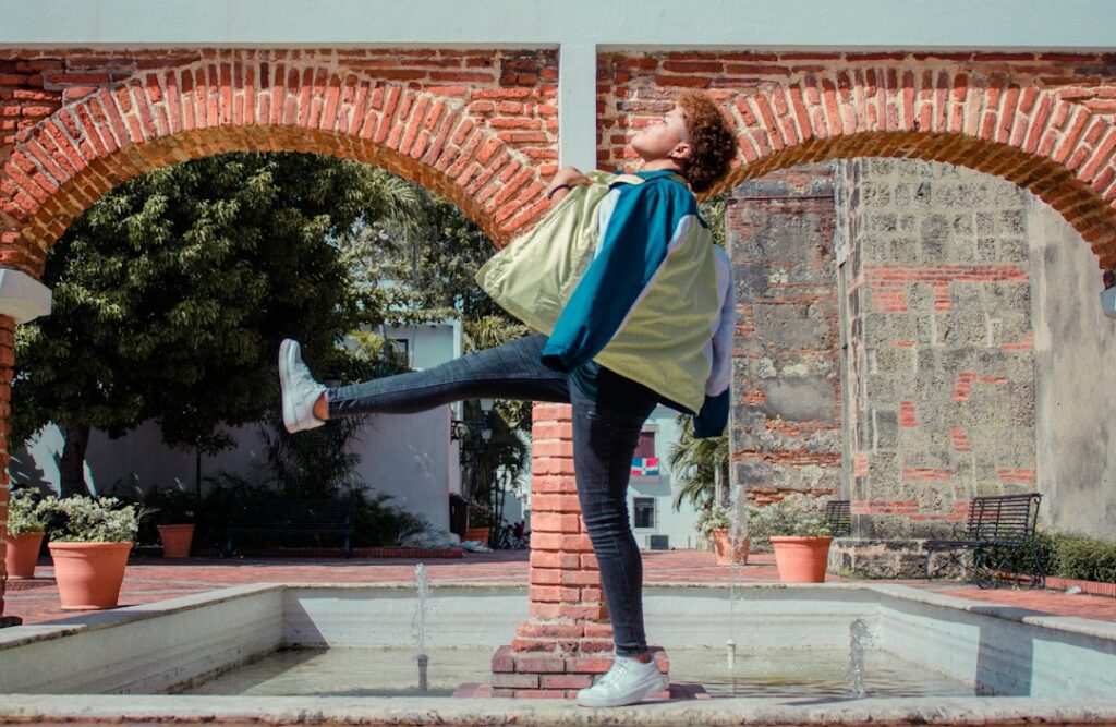 A person stretching beside a window while walking shoes and a water bottle rest nearby.